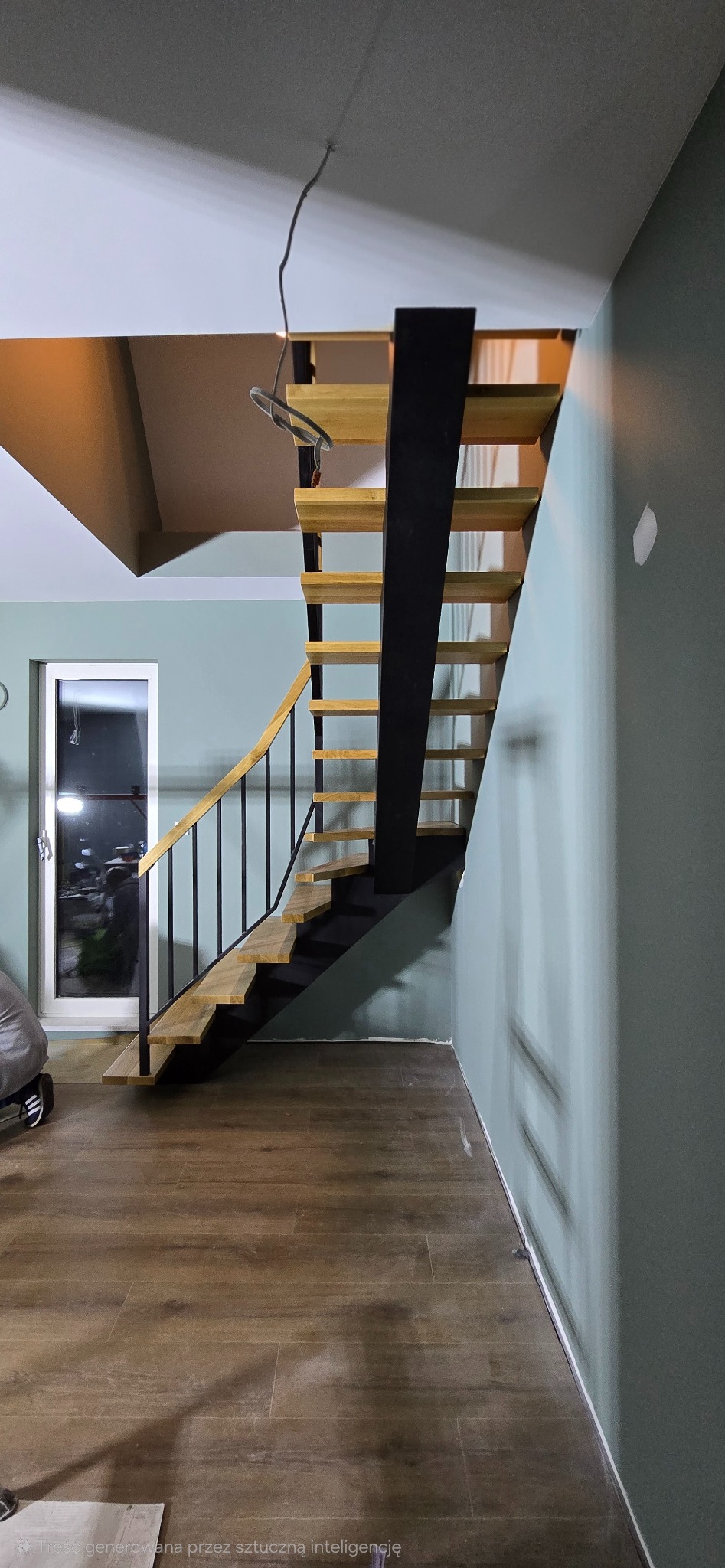 Nowoczesne schody z drewnianymi stopniami i czarną metalową konstrukcją, z drewnianą poręczą, w jasnym wnętrzu z drewnianą podłogą i zielonymi ścianami.