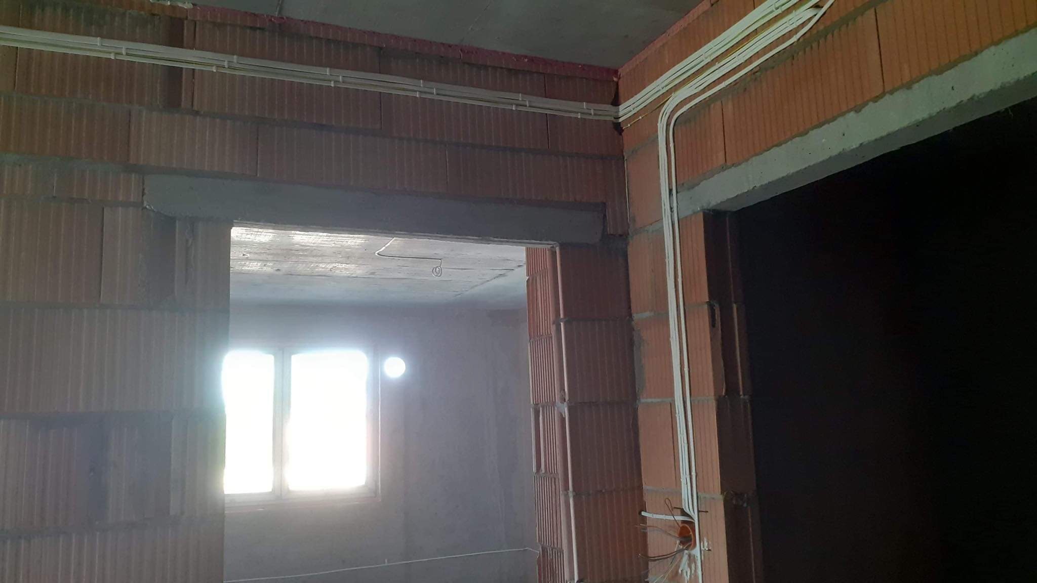 Wewnętrzne okablowanie elektryczne w rurkach PCV, prowadzone po ścianach z bloczków ceramicznych w surowym stanie, widoczne puszki instalacyjne.