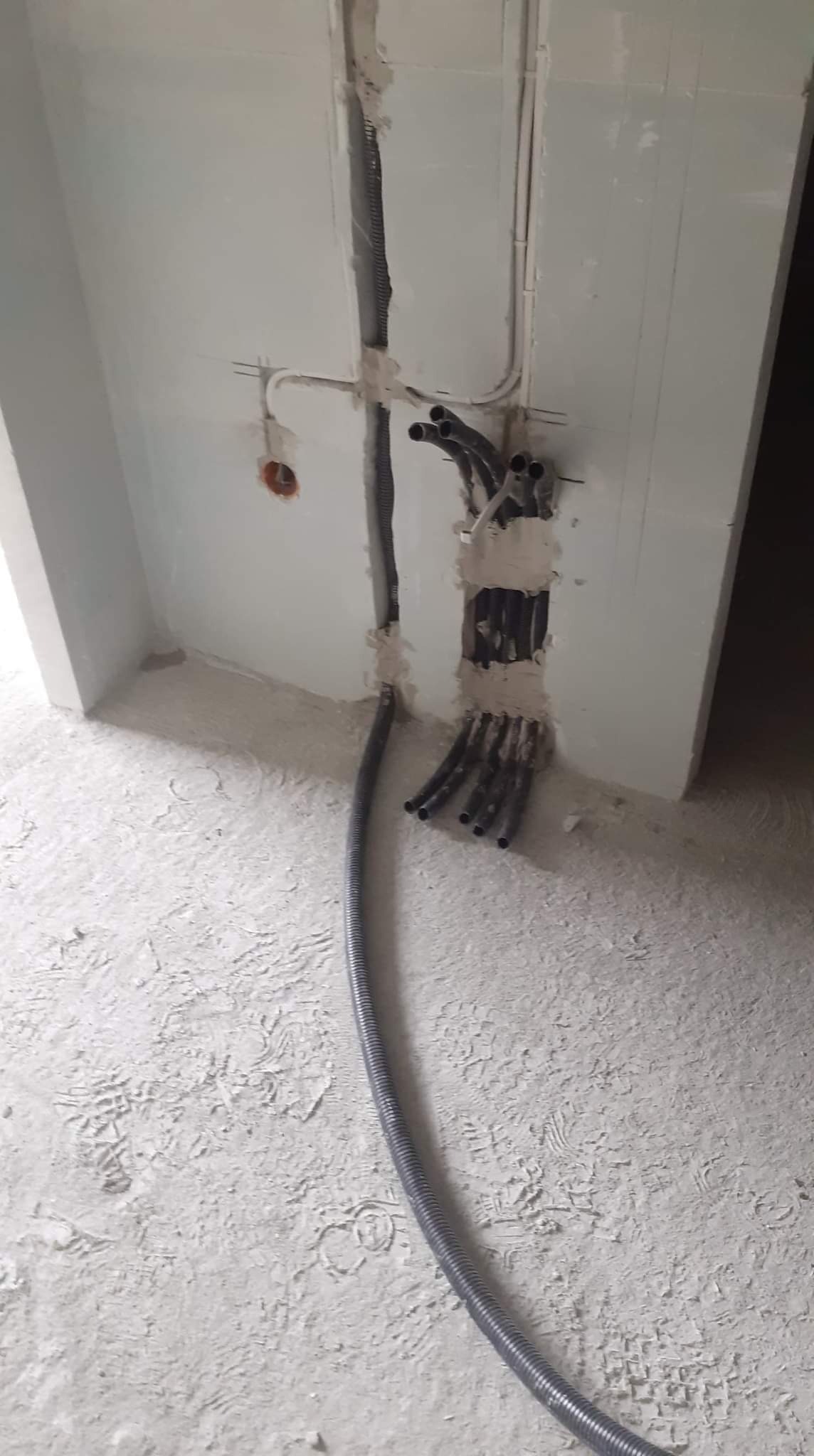 W trakcie prac: kable elektryczne w peszlach prowadzone w ścianie podczas remontu w Krakowie, widoczne ślady po zaprawie.