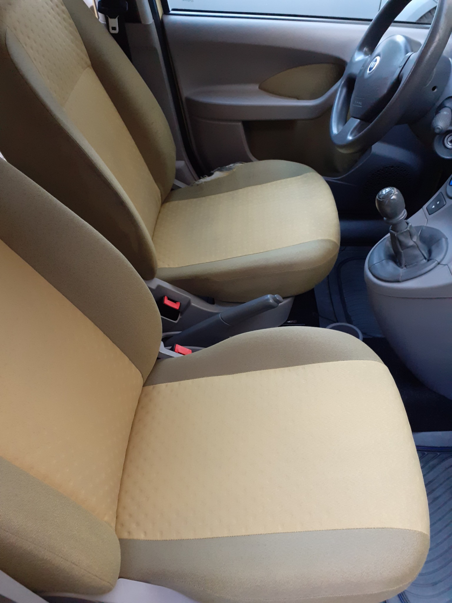 Beżowa tapicerka foteli samochodowych z widocznymi śladami użytkowania i przetarciem na siedzeniu kierowcy, wnętrze pojazdu Fiat Panda.