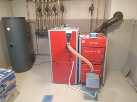 Kotłownia z dwoma kotłami Defro Smart, zasobnikiem CWU i instalacją centralnego ogrzewania z rur miedzianych w tle.