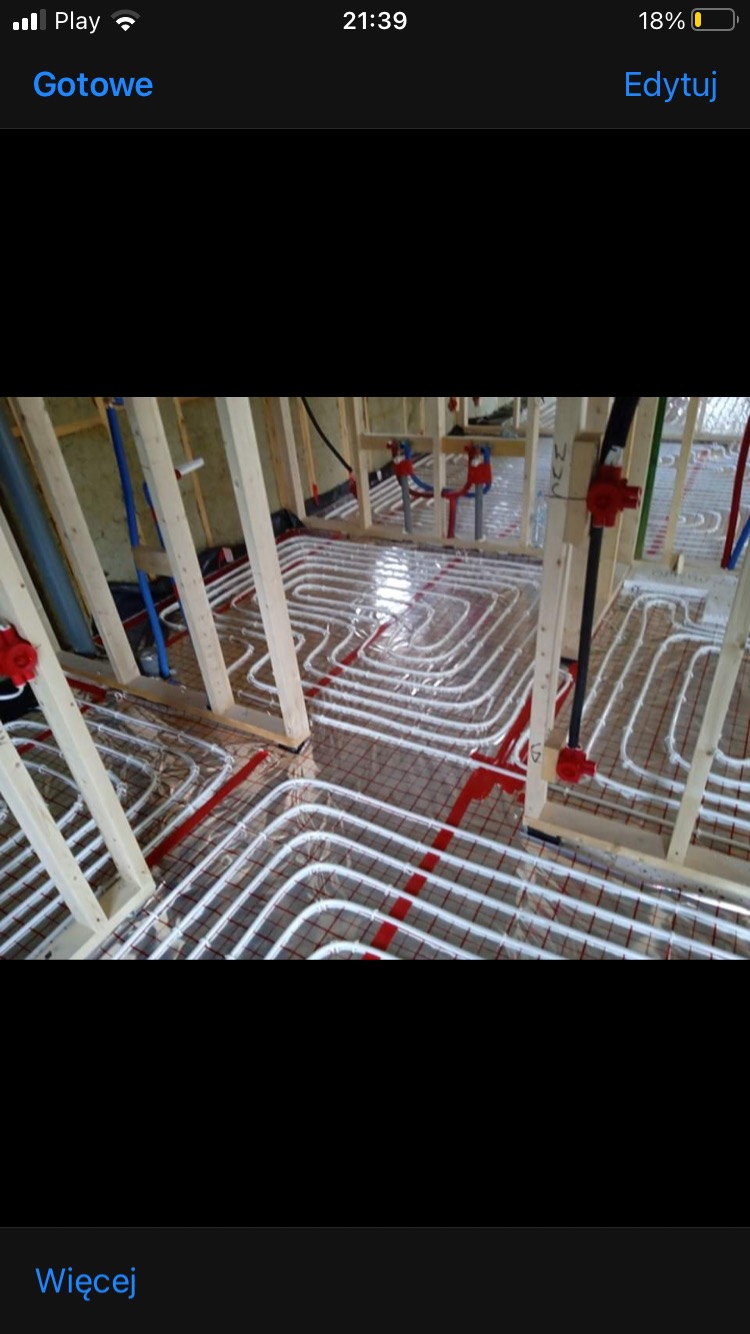 Układanie podłogowego ogrzewania wodnego w Skarszewach, rury rozprowadzone na siatce, widoczne elementy konstrukcji drewnianej.