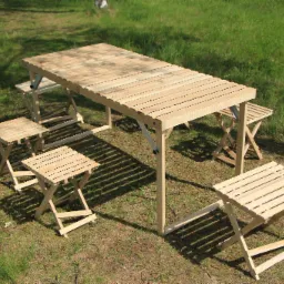 Rozkładany stół i krzesła z jasnego drewna ustawione na trawie, komplet ogrodowy.