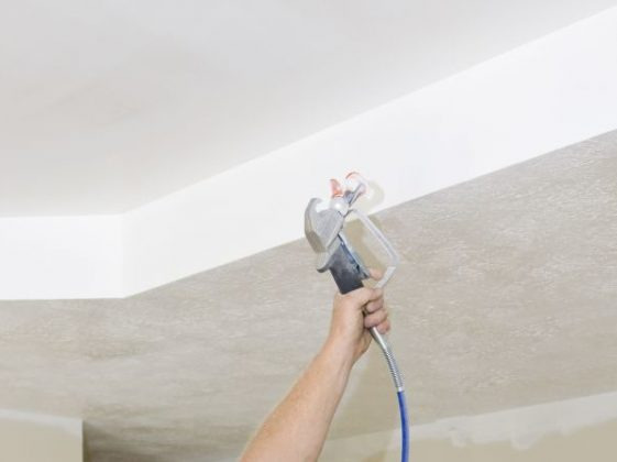 Malowanie sufitu pistoletem natryskowym; widoczna świeżo pomalowana, gładka powierzchnia i narożnik sufitu.