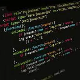 Fragment kodu JavaScript wyświetlony na ekranie komputera z ciemnym motywem, widoczne tagi <script> i <link> oraz definicje funkcji, ukośny kąt ujęcia.