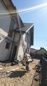 W Katowicach, podnośnik budowlany ustawiony przy ścianie domu w trakcie prac dekarskich, widoczne materiały budowlane i narzędzia.