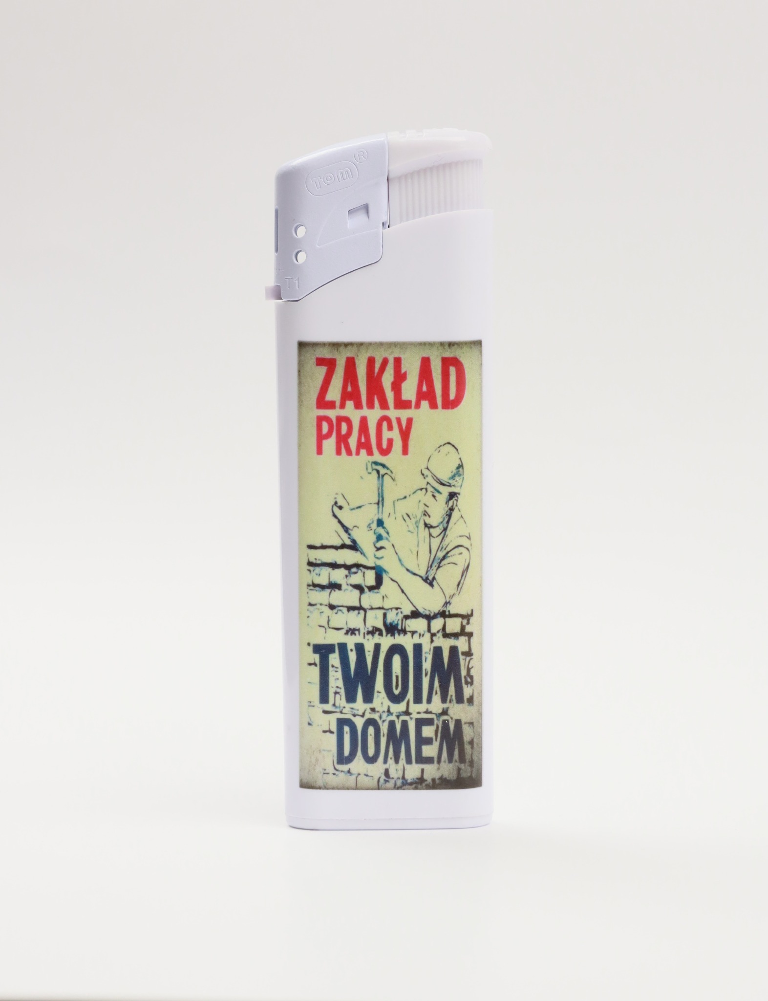 Biała zapalniczka z nadrukiem w stylu retro przedstawiającym robotnika budowlanego z młotkiem i napisem 'Zakład Pracy Twoim Domem'.