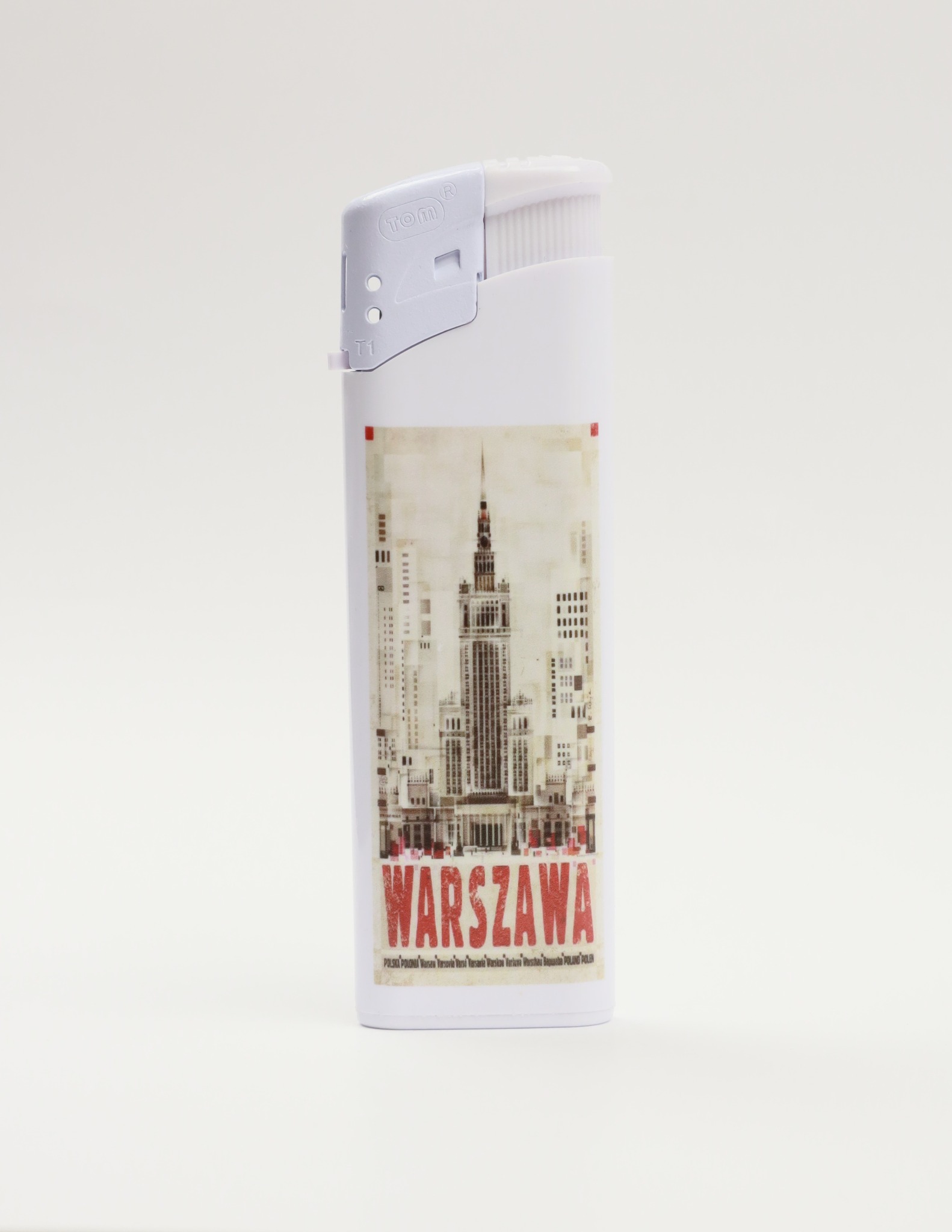 Biała zapalniczka z nadrukiem Pałacu Kultury i Nauki w Warszawie oraz napisem 'WARSZAWA' w czerwonej czcionce na białym tle.