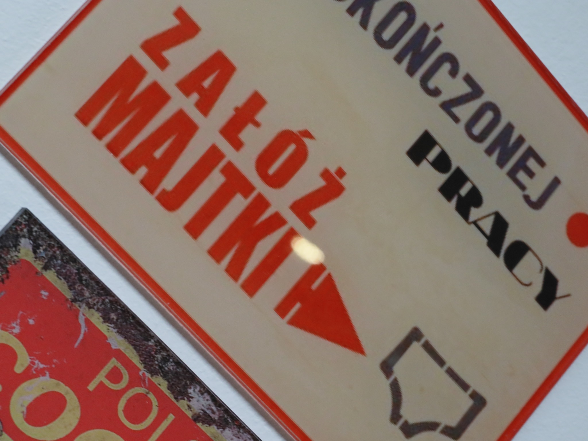 Dwie tabliczki z napisami: 'Załóż majtki' w kolorze pomarańczowym i symbolem majtek oraz 'Ukończonej pracy' w kolorze czarnym, umieszczone ukośnie.