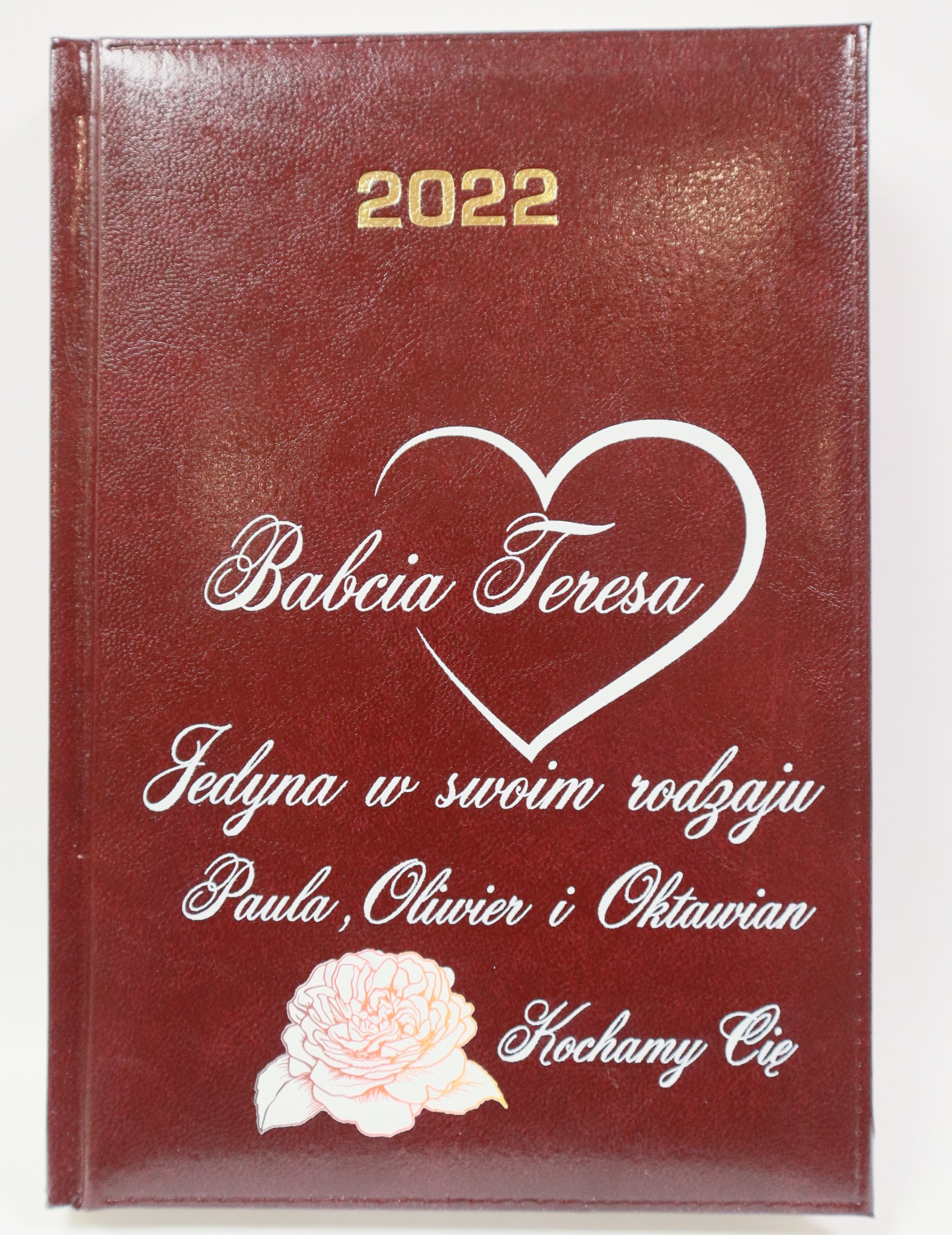 Personalizowany kalendarz na rok 2022 z imieniem Babci Teresy, dedykacją i grafiką kwiatową na okładce w kolorze burgundowym.