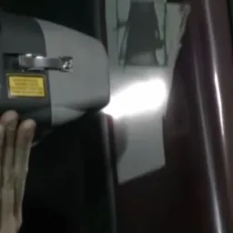 Dłoń obsługuje urządzenie laserowe do usuwania rdzy z karoserii samochodu, widoczne ślady korozji na metalu.