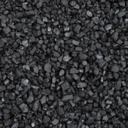 Drobny, czarny węgiel kamienny ułożony równomiernie, widoczne nieregularne kształty bryłek i refleksy światła na ich powierzchni.