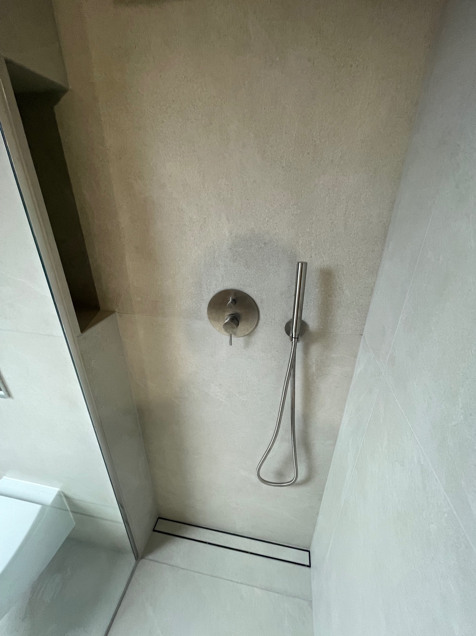 Minimalistyczna kabina prysznicowa z odpływem liniowym i deszczownicą w odcieniach szarości. Widok z góry podkreśla nowoczesny design i precyzję wykonania.