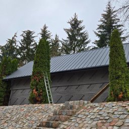 STOL-DACH MARCIN GRABOWSKI - Nowy, grafitowy dach z blachy na budynku w trakcie ocieplania, widoczna membrana Eurofol 160, drabina oparta o ścianę, kamienny murek na pierwszym planie.