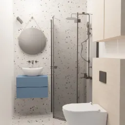 Nowoczesna łazienka z kabiną prysznicową, umywalką na niebieskiej szafce, okrągłym lustrem na sznurku i toaletą podwieszaną, wykończona płytkami lastryko.