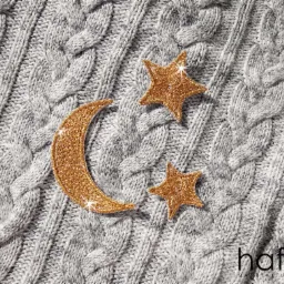 Szary sweter z warkoczowym splotem z haftowanymi złotymi gwiazdami i księżycem oraz logo firmy hafna