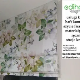 Zasłona rzymska z motywem kwiatowym, wykonana w Kazimierzy Wielkiej, widoczna z bliska, częściowo zasłania logo firmy.