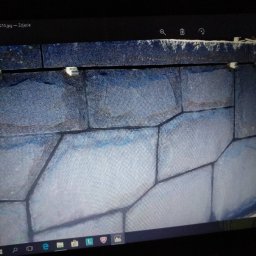 KAMSTEN kamieniarstwo budowlane - Fragment ściany wyłożonej nieregularnymi, szarymi kamieniami z widocznymi spoinami, sfotografowany z bliska pod kątem.