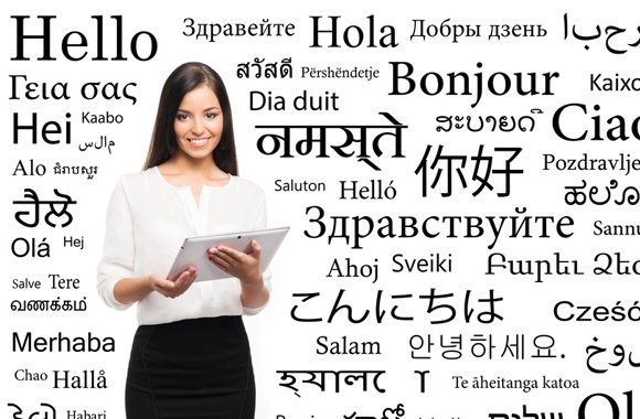 Uśmiechnięta kobieta trzyma tablet na tle napisu 'Hello' i innych powitań w różnych językach.
