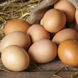 Brązowe i beżowe produkty spożywcze ułożone na drewnianym stole w jutowym worku i na sianie.