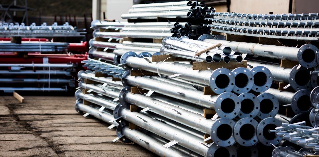 Stosy ocynkowanych rur stalowych z kołnierzami na drewnianych paletach, gotowe do montażu.