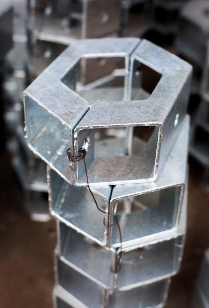 Stalowe, ocynkowane profile zamknięte o przekroju sześciokątnym, połączone drutem w stos, przygotowane do dalszej obróbki lub montażu.