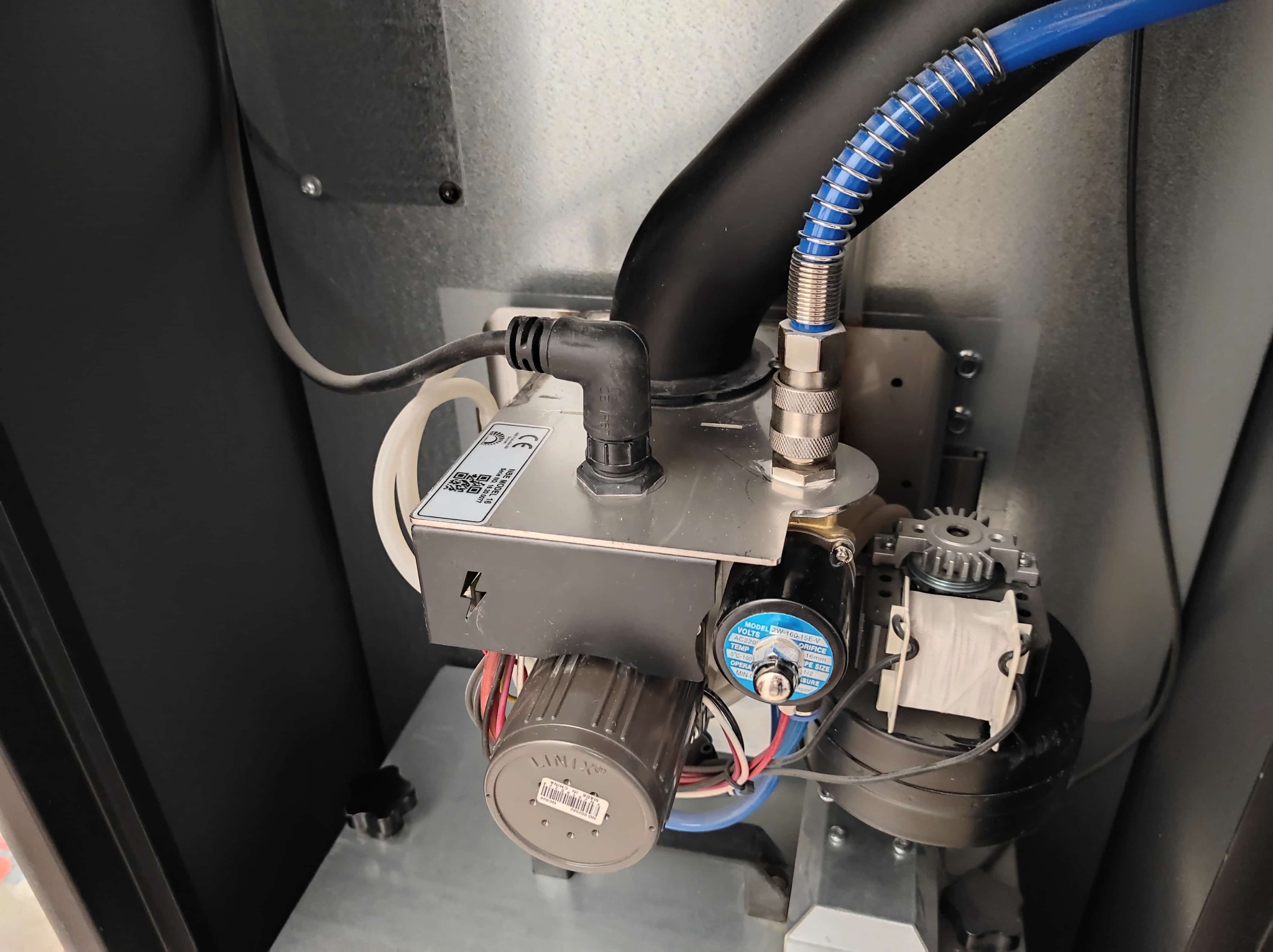 Elementy instalacji: zawór elektromagnetyczny z cewką LINIX, przewody pneumatyczne w oplocie, złącza gwintowane i rury wewnątrz obudowy urządzenia.