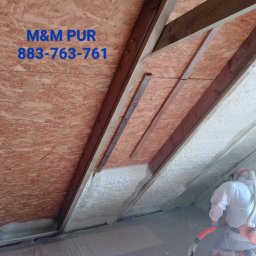 M&M PUR - Poddasze ocieplane pianką natryskową, widoczny pracownik w kombinezonie ochronnym aplikujący izolację między krokwiami. Na ścianie widoczny napis 'M&M PUR 883-763-761'.