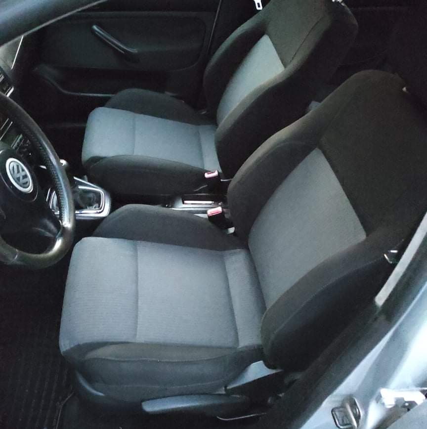 Wnętrze samochodu Volkswagen Golf IV z dwukolorową tapicerką foteli (szaro-czarną) po czyszczeniu, widoczne detale deski rozdzielczej i kierownicy z logo VW.