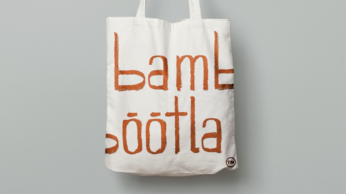 Płócienna torba na zakupy z brązowym nadrukiem napisu 'Lamble söötla' na szarym tle.