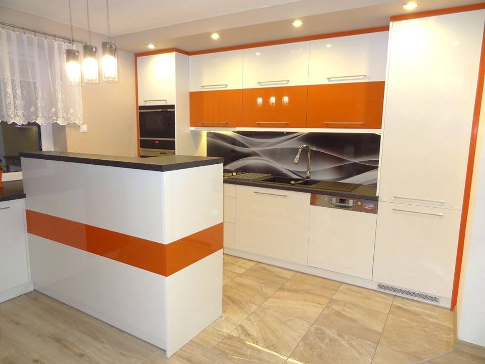 Nowoczesna kuchnia z białymi szafkami i pomarańczowymi akcentami, czarny blat, wyspa kuchenna z pomarańczowym pasem, wzorzysty panel nad blatem i podłoga z płytek imitujących drewno.