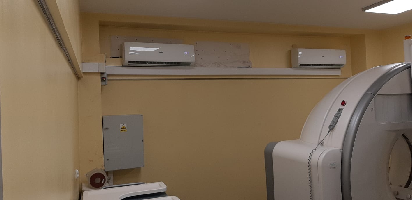 Dwa klimatyzatory ścienne Haier zamontowane w pomieszczeniu z aparaturą medyczną, widoczne ślady po poprzedniej instalacji.