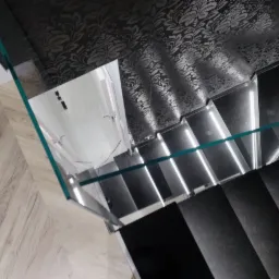Nowoczesne schody z podświetlanymi stopniami i szklaną balustradą, widok z g&oacute;ry, wzorzysta tapeta w tle.