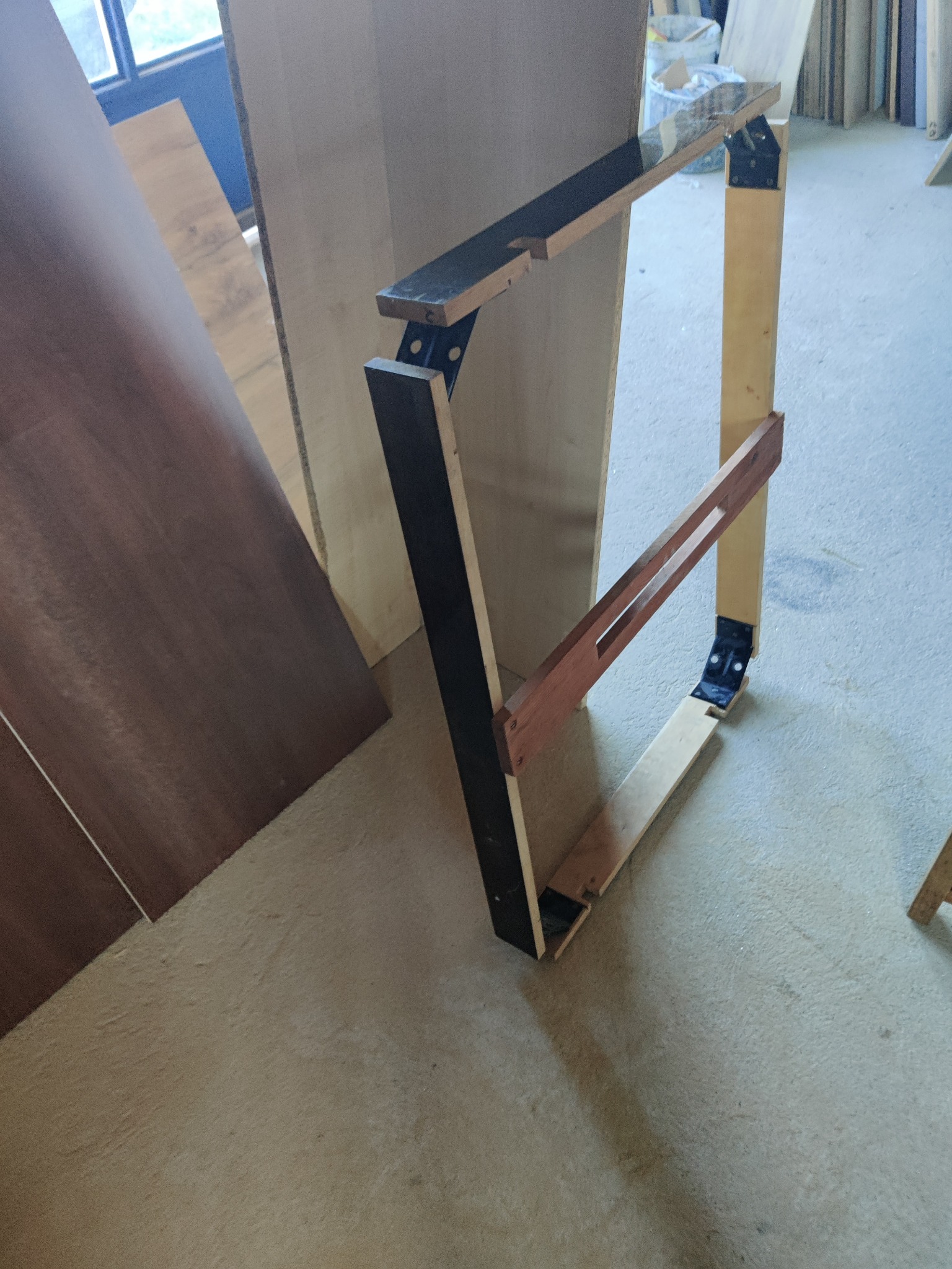 Konstrukcja ramy drewnianej z elementami metalowymi, prawdopodobnie w trakcie montażu, widoczne surowe drewno i elementy łączące.