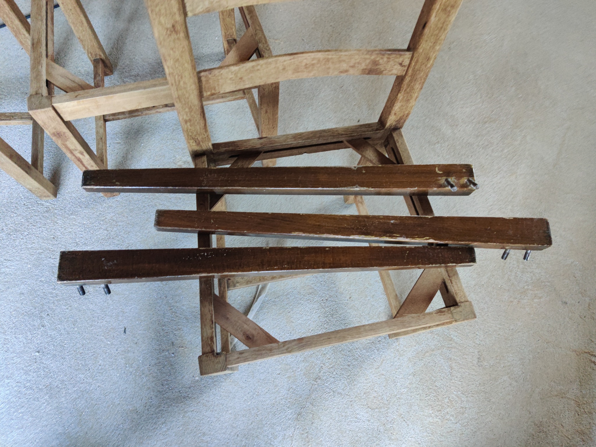 Fragment drewnianej konstrukcji, prawdopodobnie altany lub pergoli, z widocznymi elementami montażowymi i surowym wykończeniem, leżący na szarej powierzchni.