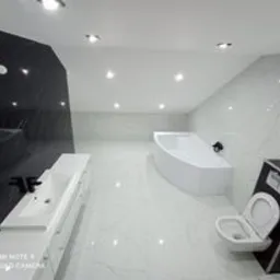 Nowoczesna łazienka na poddaszu z czarno-białymi płytkami imitującymi marmur, białą armaturą, asymetryczną wanną i długim blatem z umywalką.