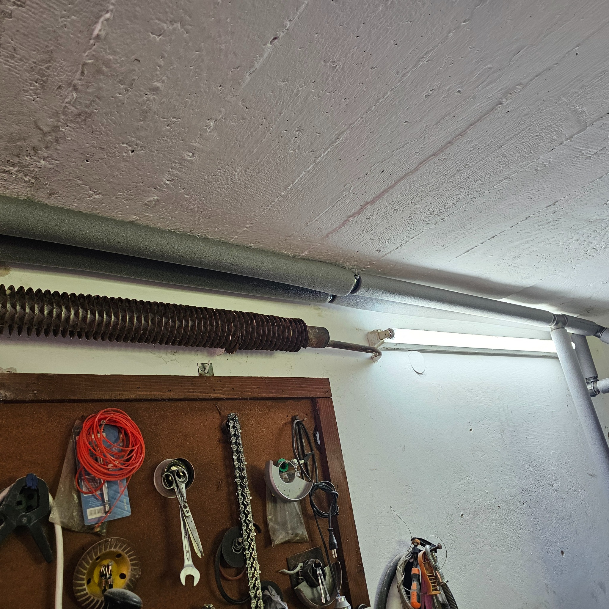 Rury grzewcze z izolacją termiczną pod sufitem w Wilkołazie, widoczna również spirala grzewcza i tablica z narzędziami.