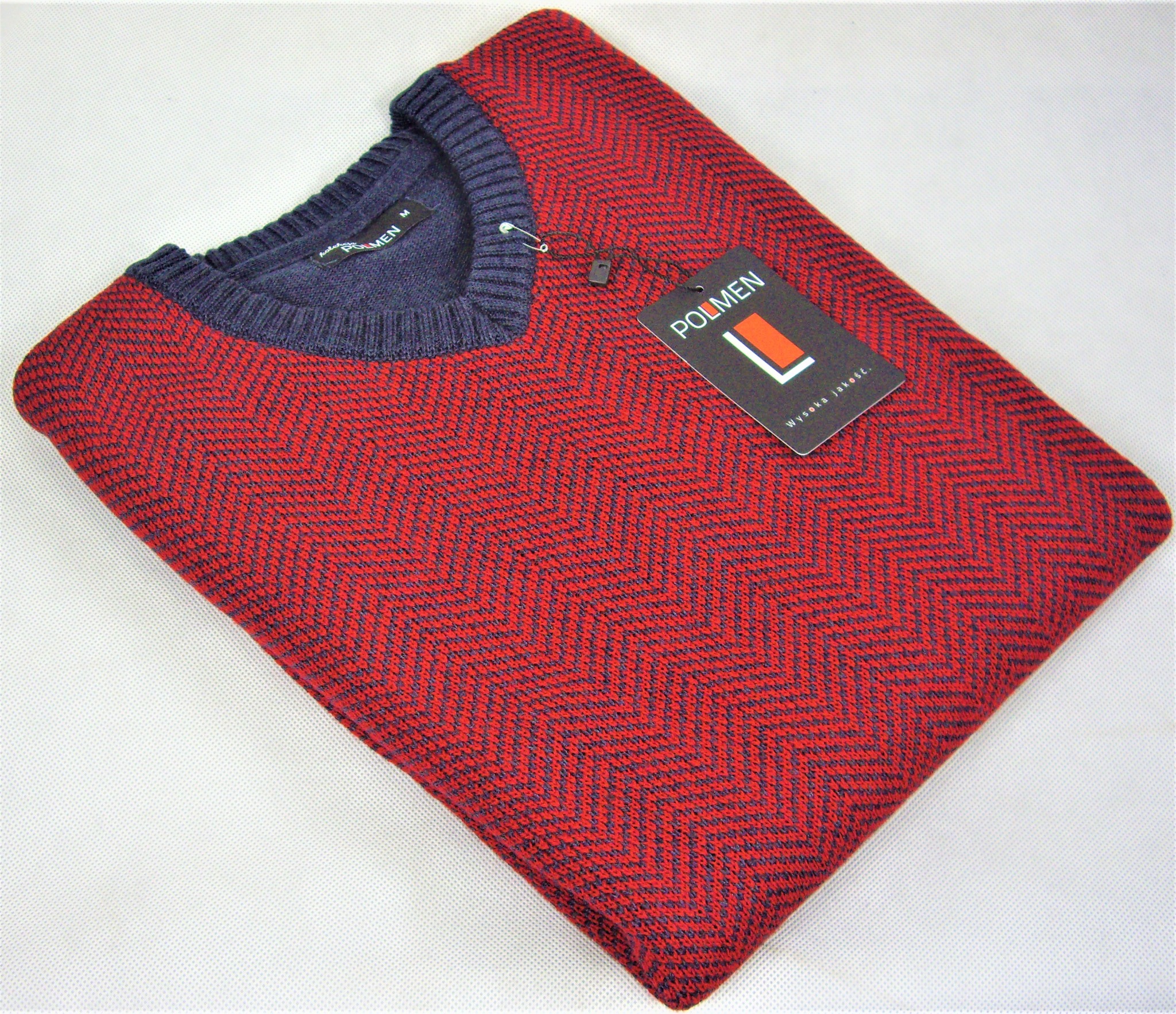 Czerwono-granatowy sweter męski w jodełkę marki Polmen, złożony na białym tle, z widoczną metką z logo.