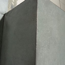 JANO Uslugi remontowe - Szary narożnik ściany po świeżo nałożonej gładzi, widoczne niedoskonałości i nierówności powierzchni przed szlifowaniem.