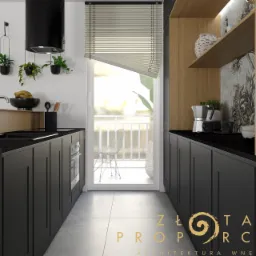 Nowoczesna kuchnia w odcieniach czerni i drewna z widokiem na balkon, minimalistyczne dodatki, rolety okienne częściowo zasłonięte, na blacie ekspres do kawy i rośliny, dekoracyjna tapeta w tle.