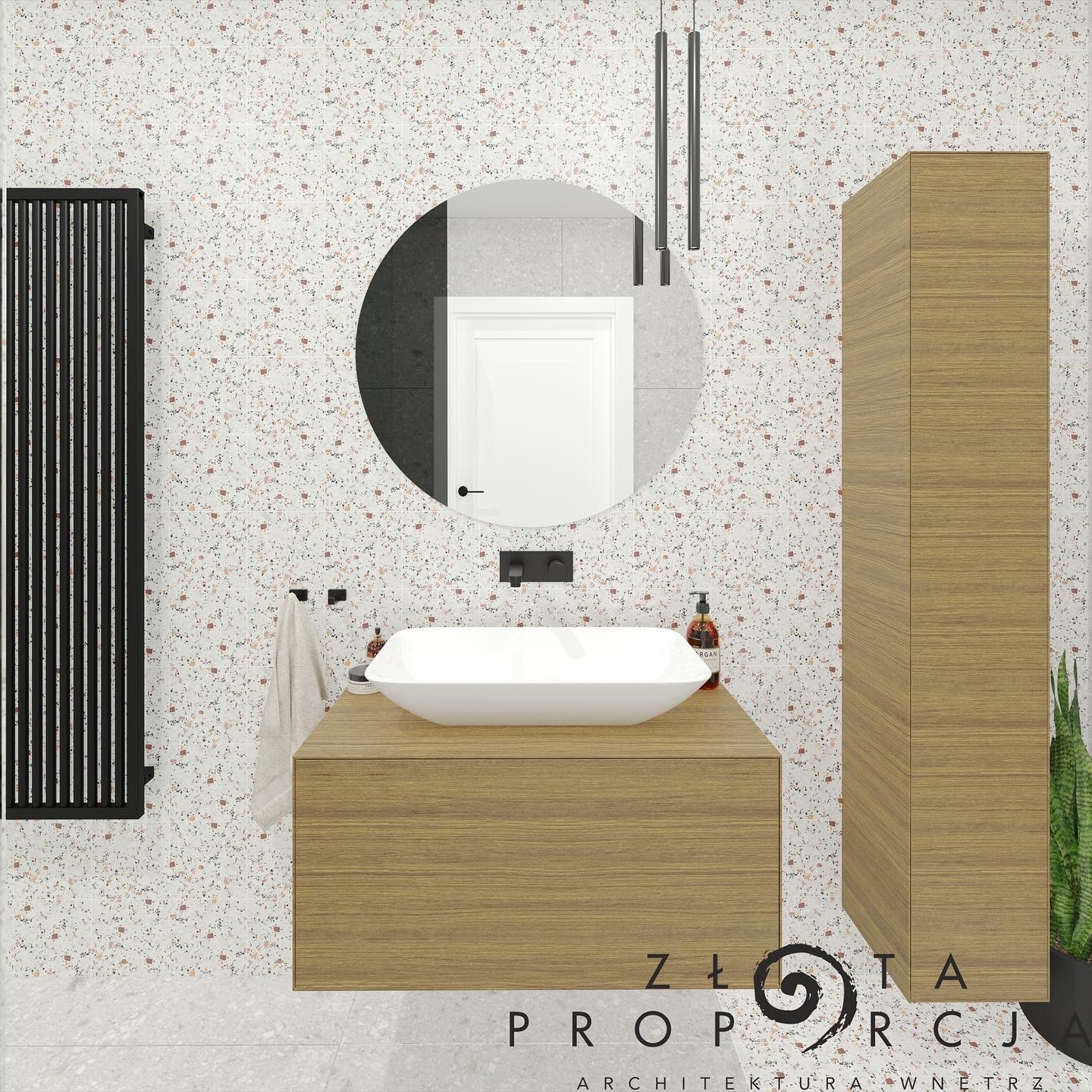 Wizualizacja łazienki z umywalką nablatową, okrągłym lustrem i grzejnikiem żeberkowym na ścianie z mozaiką terazzo.