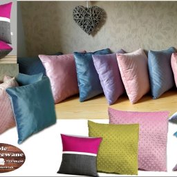 Meble Tapicerowane Paweł Szymkowiak - Dekoracyjne poduszki tapicerowane w różnych kolorach i wzorach, ułożone na drewnianej podłodze. W tle ściana z delikatnym wzorem i dekoracja w kształcie serca.