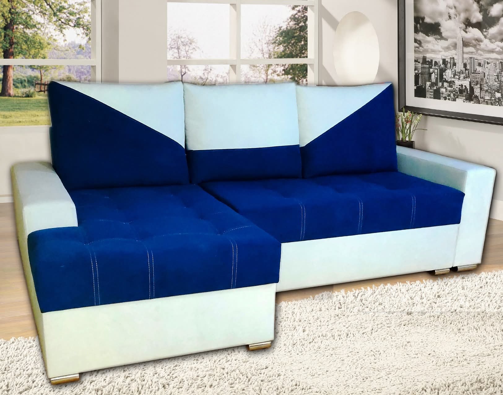 Rozkładana sofa narożna w kolorze granatowo-białym z geometrycznym wzorem na poduszkach, na tle okna i obrazu z panoramą miasta.