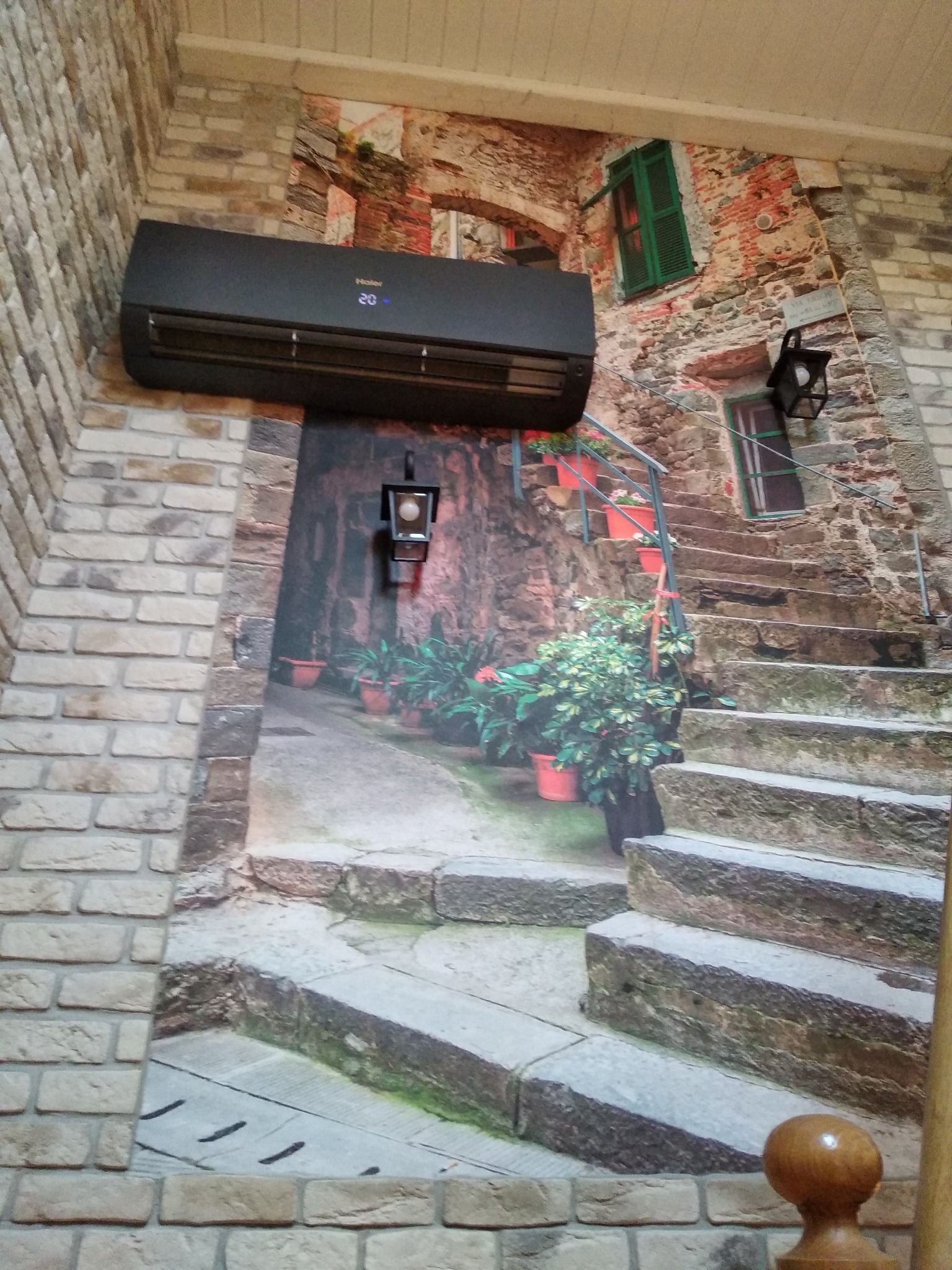 Czarny klimatyzator Haier zamontowany na ścianie z fototapetą imitującą włoskie schody w Łukowie.