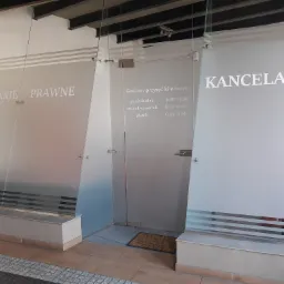 Wejście do kancelarii prawnej w Chorzowie, z przeszklonymi drzwiami z napisem 'Kancelarie Prawne' i informacją o godzinach przyjęć klientów.