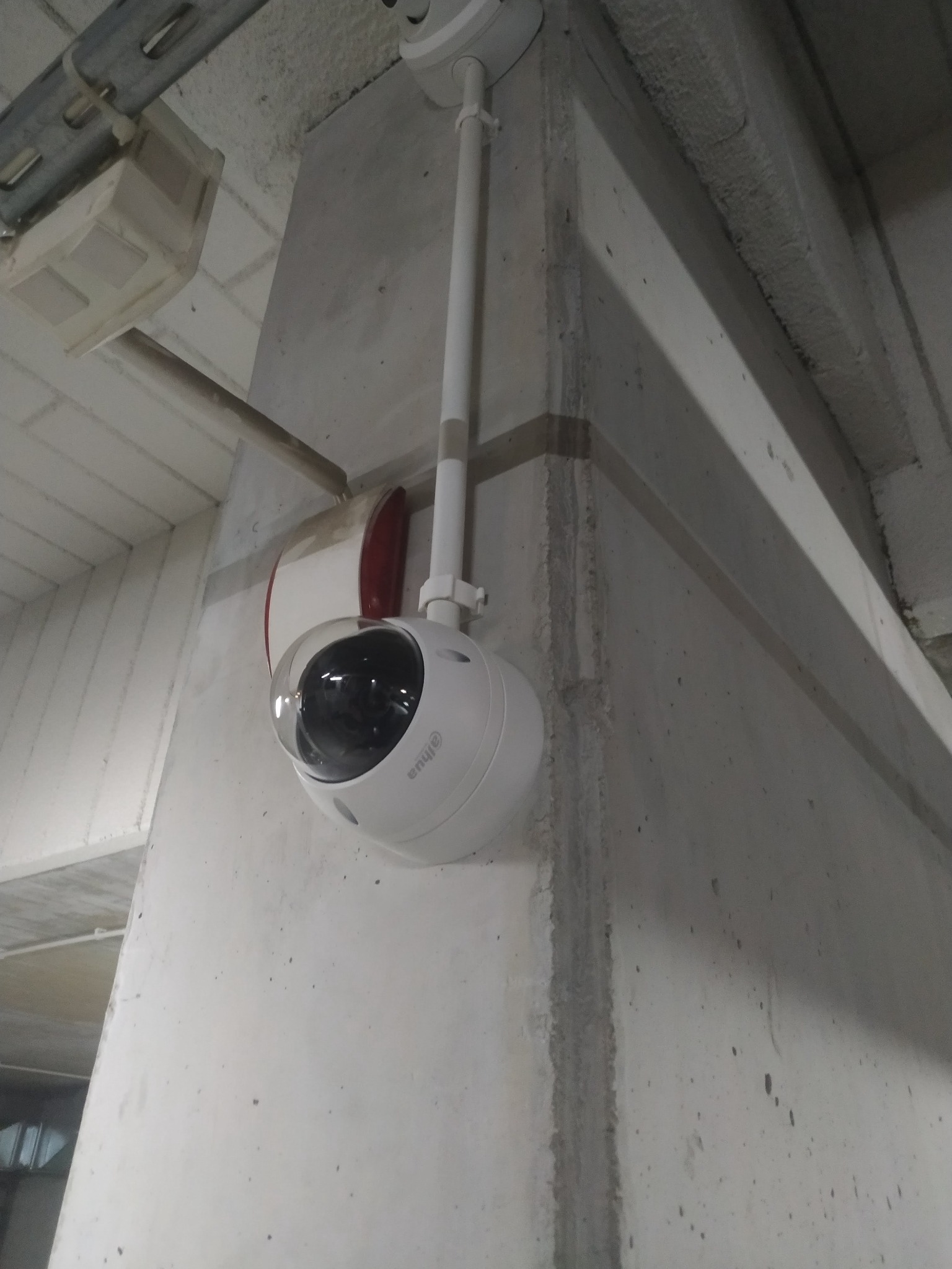 Kamera kopułkowa Dahua zamontowana na betonowym słupie w garażu podziemnym, widoczna instalacja elektryczna.