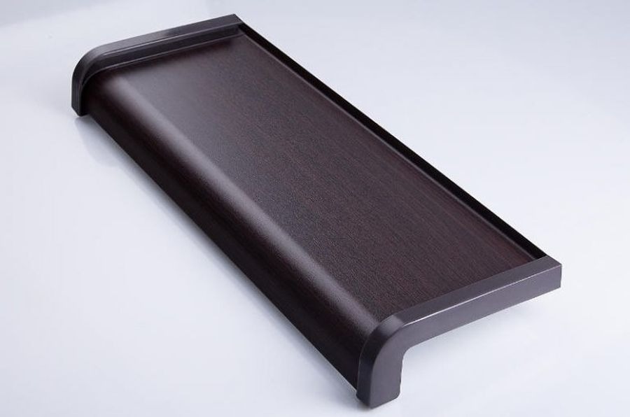 Brązowy, laminowany element wykończeniowy z zaokrąglonym narożnikiem, imitujący drewno, leżący na białym tle.