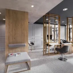 Nowoczesne wnętrze salonu fryzjerskiego z jasnymi ścianami, drewnianymi elementami i szarymi fotelami fryzjerskimi. Widoczne stanowiska pracy z lustrami i profesjonalnym sprzętem.