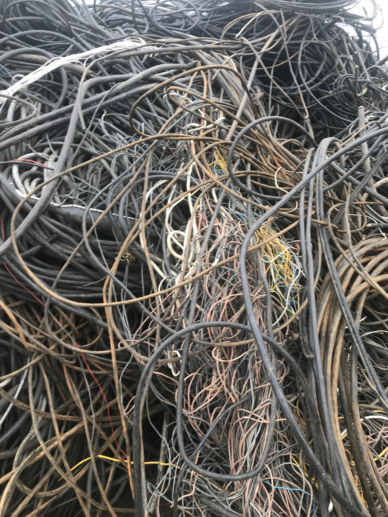Stos czarnych i brązowych kabli w nieładzie, widoczne również pojedyncze kable w kolorze białym, żółtym i niebieskim.