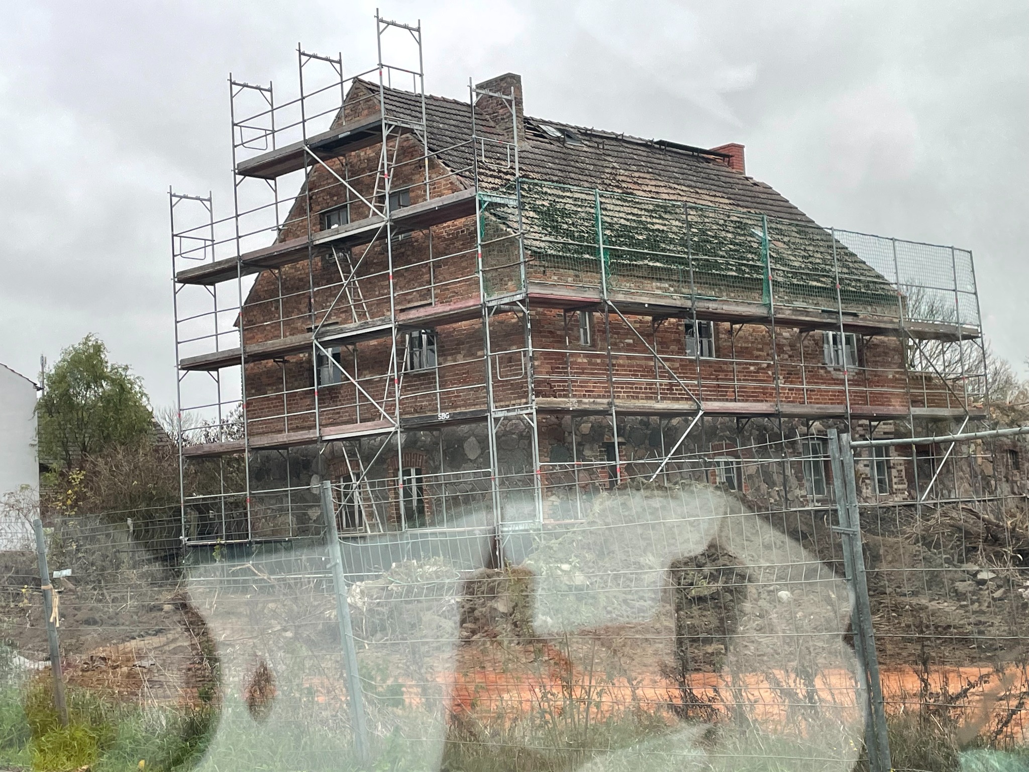 Stare, ceglane zabudowanie w Rzepinie, otoczone rusztowaniem i siatką zabezpieczającą podczas prac wysokościowych. Część dachu pokryta mchem, widoczne ślady renowacji.